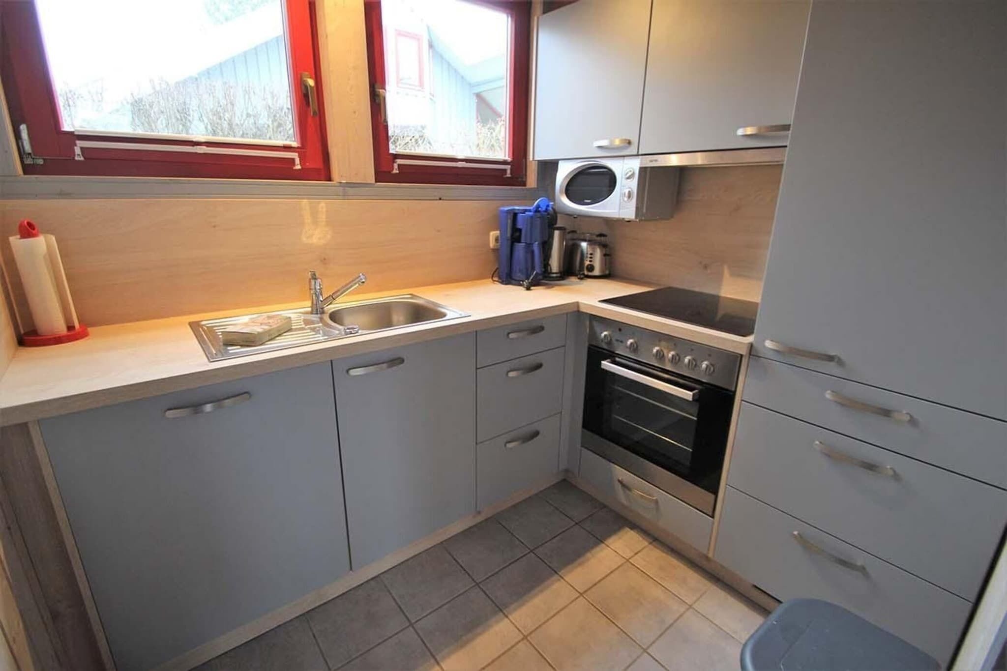 A compact kitchen with a sink, stove, and microwave.