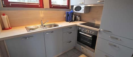 A compact kitchen with a sink, stove, and microwave.