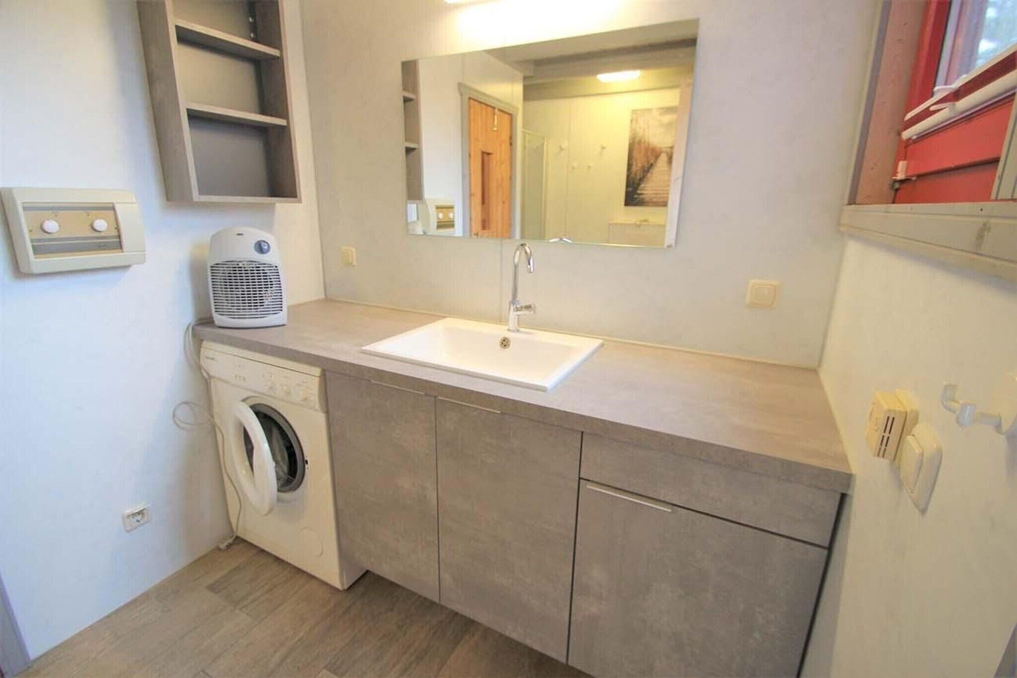 Ein kleines Badezimmer mit Waschmaschine, Waschbecken und Spiegel.