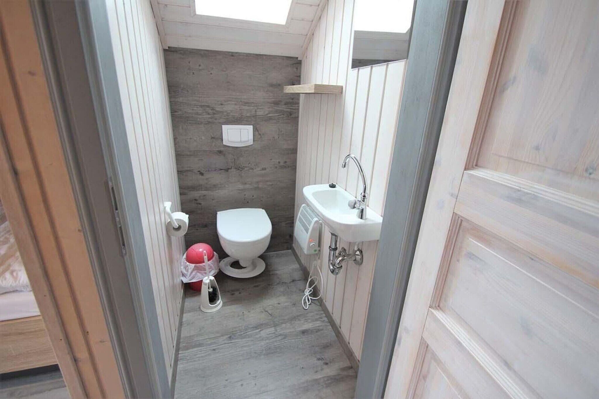 Un baño pequeño con inodoro, lavamanos y paredes de madera.