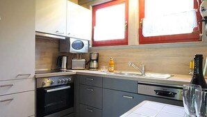 Cocina compacta con microondas, tostadora, cafetera y lavabo.