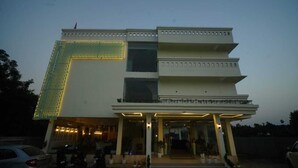 A multi-story hotel with a distinctive geometric facade, a covered entrance, and a well-lit exterior. - Hotel Garnet (Bokakhat)