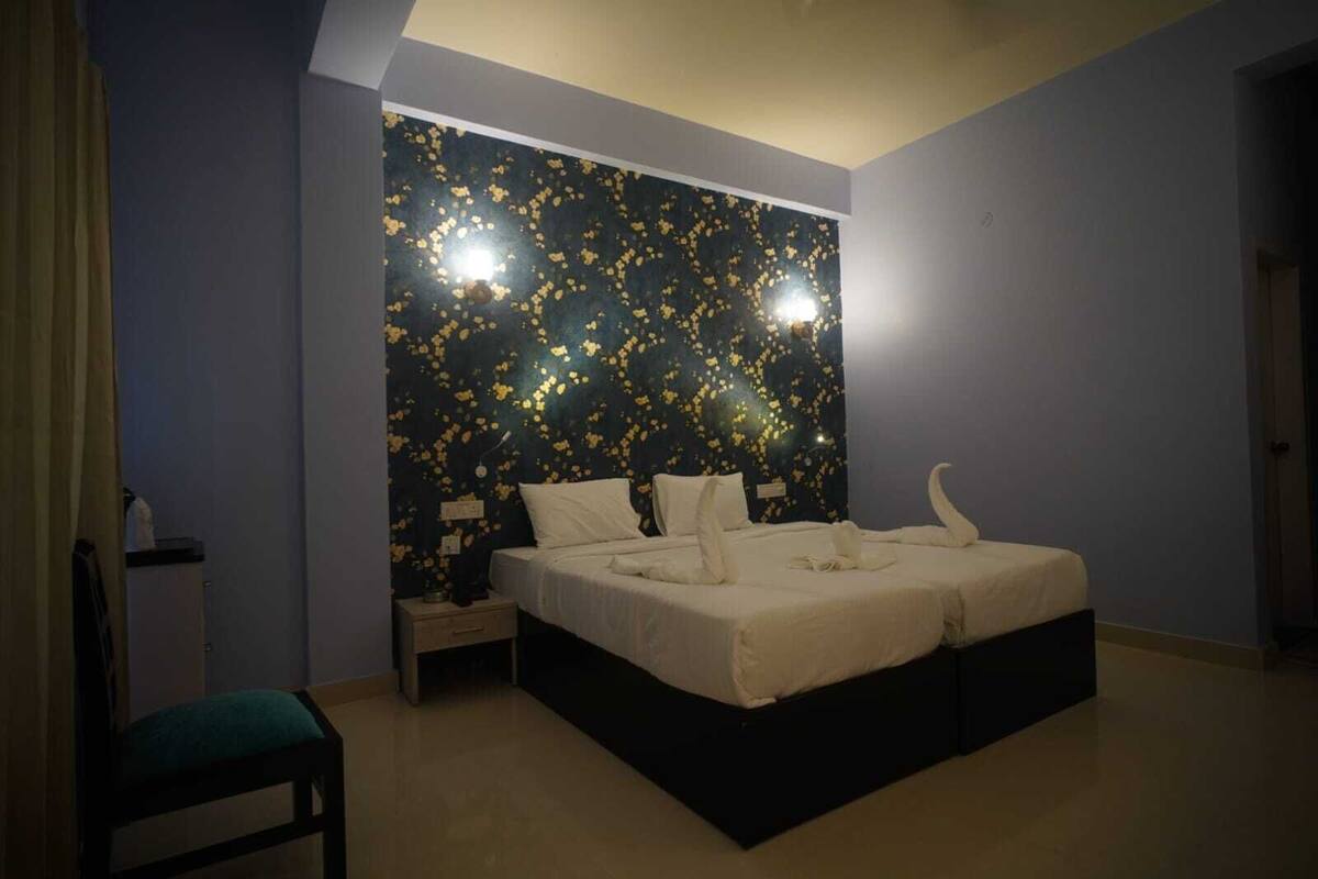 A bedroom with a bed, a nightstand, a chair, and a wall with a star pattern.
