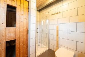 Bathroom features a glass-enclosed shower area and a white toilet.