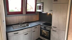 Una cocina compacta con fregadero, hornilla, horno y microondas.