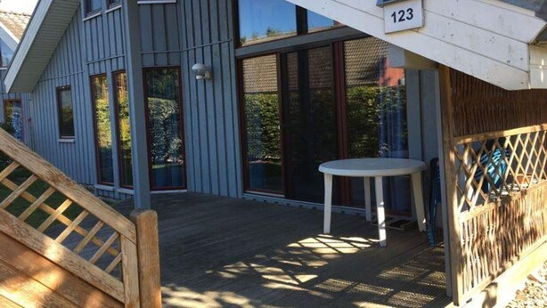 Una casa moderna con una terrazza, ampie finestre e il numero 123.