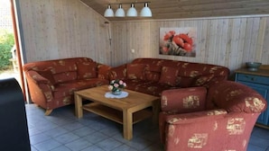 Un accogliente soggiorno con un divano rosso decorato con motivi, un tavolino in legno e un quadro con fiori al muro.
