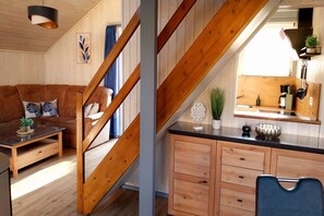 A wooden interior with a staircase, a sofa, a coffee table, and a kitchen area. - exklusives skandinavisches Ferienhaus (Granzow)