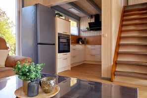 Une cuisine moderne équipée d’un four encastré, d’un réfrigérateur et de meubles de rangement en bois.