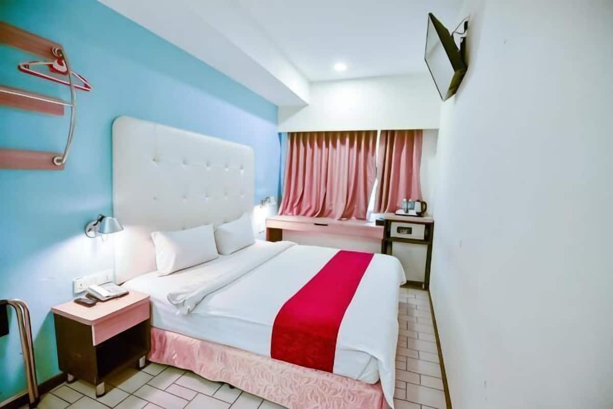 A hotel room with a large bed, bedside tables, a desk, and a chair.