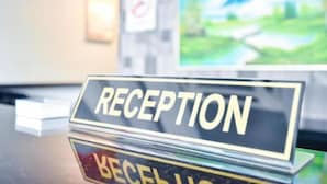 Un comptoir d’accueil avec une pancarte indiquant « RÉCEPTION » et, en arrière-plan, un panneau « Il est interdit de fumer ».