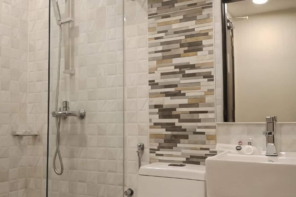 A shower with a glass door, a toilet, and a sink with a mirror.