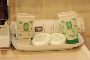 Ein Tablett mit verschiedenen Pflegeprodukten, darunter Duschgel, Bodylotion und Shampoo, allesamt mit dem Logo des Ritz Garden Hotels versehen.