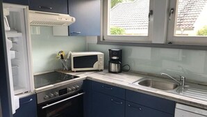 Una cocina compacta con estufa, microondas, cafetera y lavabo.