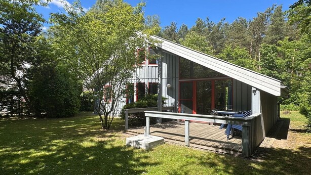 A modern wooden cabin with a deck, surrounded by trees. - exklusives skandinavisches Ferienhaus (Granzow)