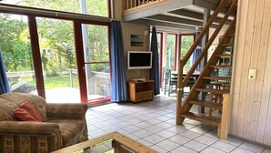A spacious living area with a sofa, a coffee table, a TV, and a staircase leading to an upper level. - exklusives skandinavisches Ferienhaus (Granzow)