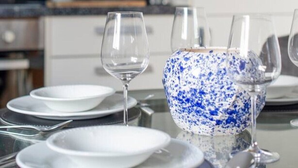 A dining table set with plates, glasses, and a blue speckled bowl. - Ealing 3 Bath Flat w/ Parking | 10 mins to Station (London)