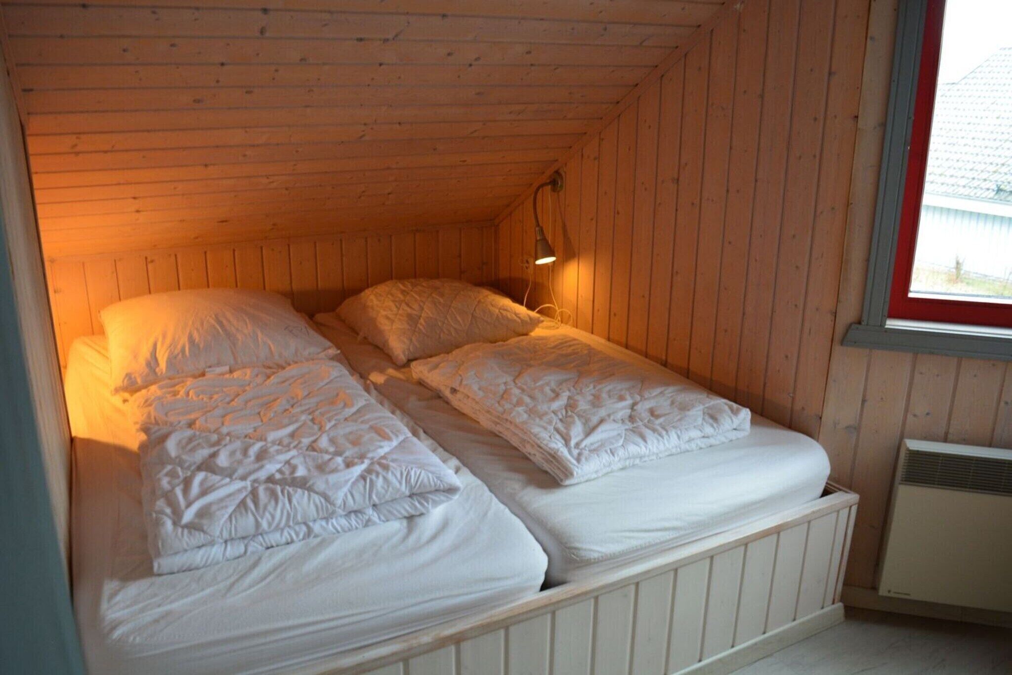 A single bed with a headboard, a bedside lamp, and a window with a view of a building outside.