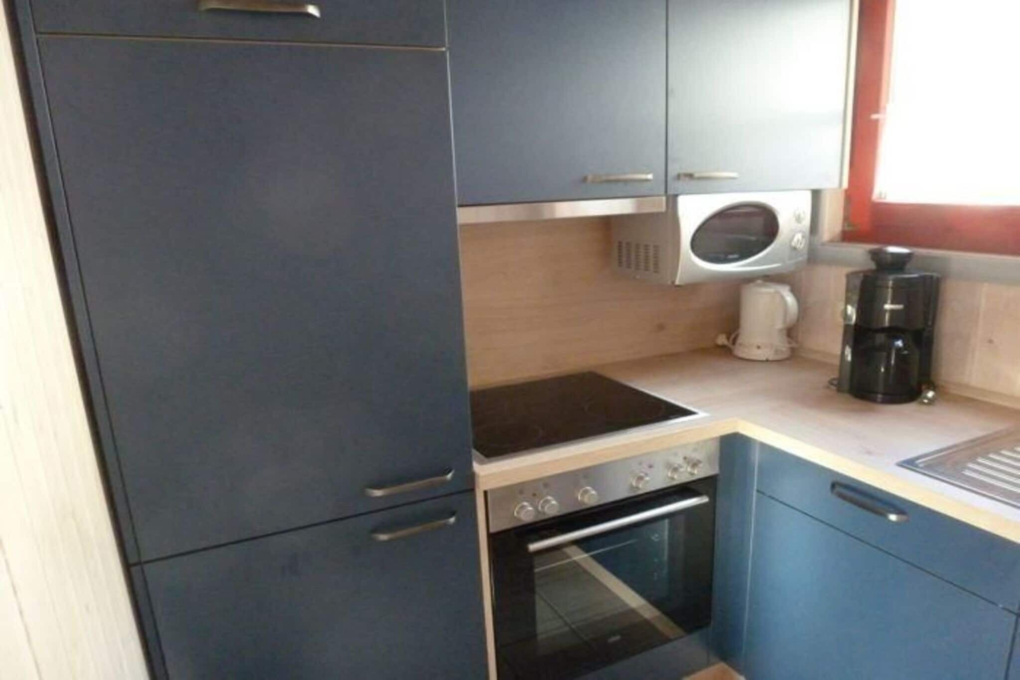 Una cucina compatta con forno a microonde, macchina del caffè e forno.
