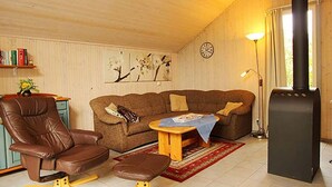 Una sala de estar acogedora con un sillón de cuero marrón, un sofá marrón, una mesa de centro de madera y una chimenea.