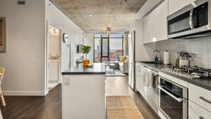 Una cocina moderna con una isla central, electrodomésticos de acero inoxidable y vistas al área de estar.