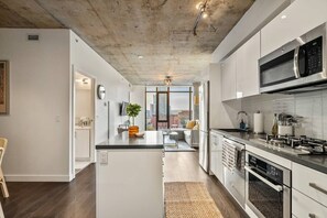 Uma cozinha moderna com ilha central, eletrodomésticos de aço inoxidável e vista para a sala de estar.