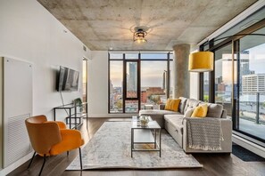 Uma sala de estar moderna com uma janela grande, um sofá, uma mesa de centro e uma televisão.