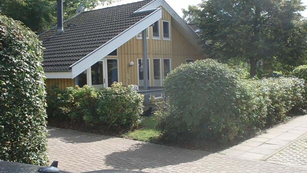 A two-story house with a sloped roof, a chimney, and a paved driveway. - exklusives skandinavisches Ferienhaus (Granzow)