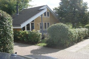 Ett tvåvåningshus med ett sluttande tak, en skorsten och en asfalterad uppfart.