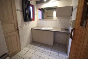 A small, clean bathroom with a white sink, a mirror, and a wooden door. - exklusives skandinavisches Ferienhaus (Granzow)