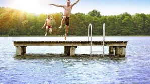 A concrete pier extending into a body of water with a metal ladder, surrounded by a forested area. - exklusives skandinavisches Ferienhaus (Granzow)