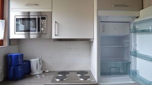 Uma cozinha com micro-ondas integrado, fogão e geladeira com porta de vidro.