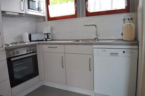 Una cocina compacta equipada con microondas, cafetera, horno y lavavajillas.