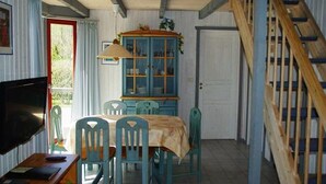 Un comedor con una mesa y sillas, un armario con puertas de vidrio, un televisor y una escalera.
