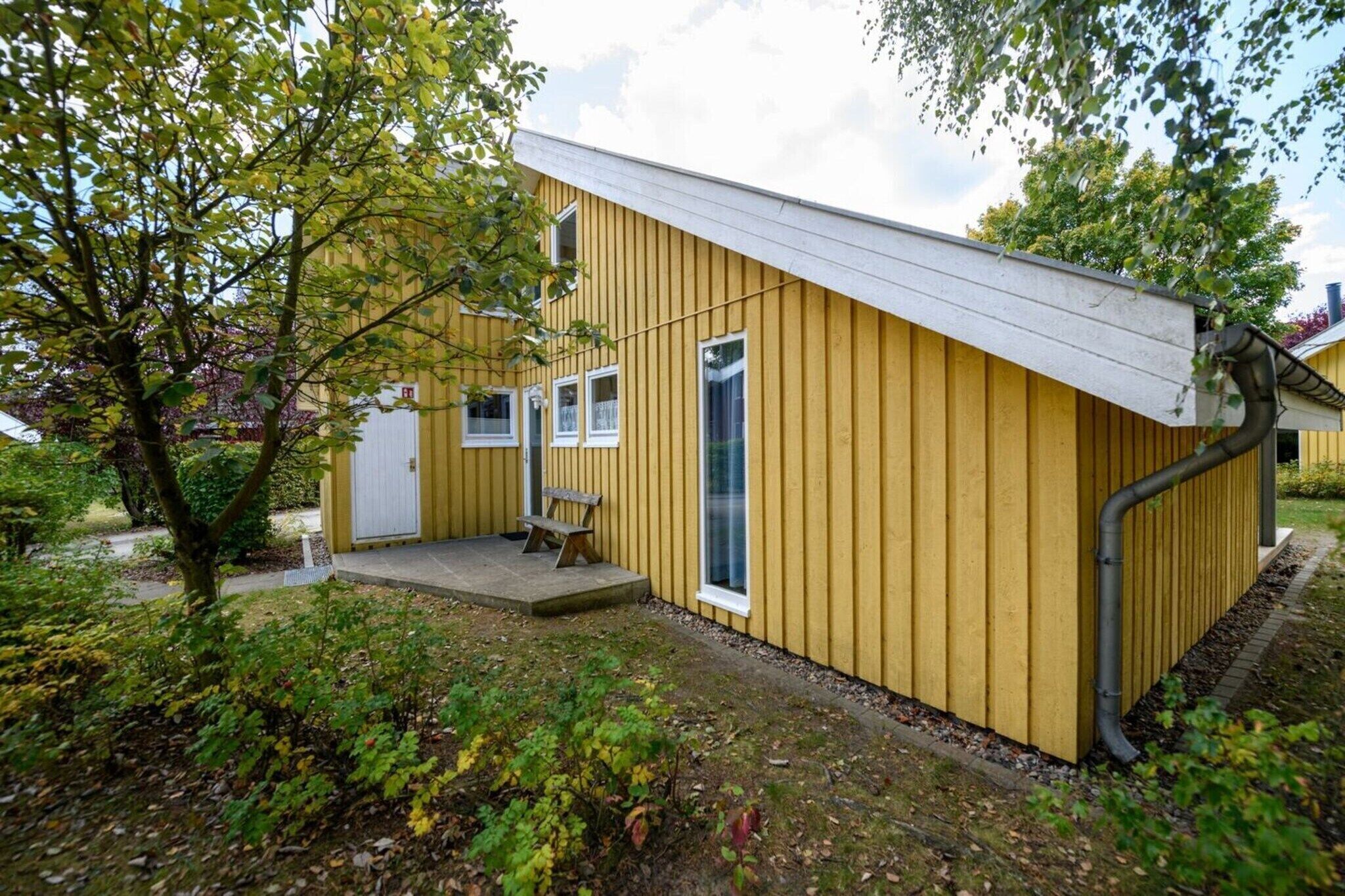 A yellow building with a white roof, a door, and a window.