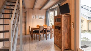 A wooden interior with a dining area, staircase, and a television mounted on the wall. - skandinavisches Ferienhaus in Mirow (Granzow)