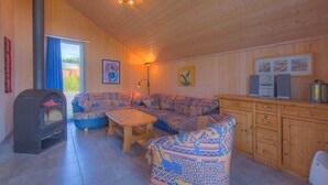 L’intérieur d’un chalet accueillant, avec un plafond en bois, un ensemble de canapés, une table basse et une cheminée.