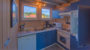 Une cuisine de taille réduite avec des murs en bois, une cuisinière, un four à micro-ondes et un évier.