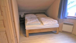 Un letto singolo in una stanza con pareti in legno e soffitto spiovente.
