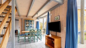 Un intérieur en bois comprenant un coin repas, un téléviseur et un escalier.