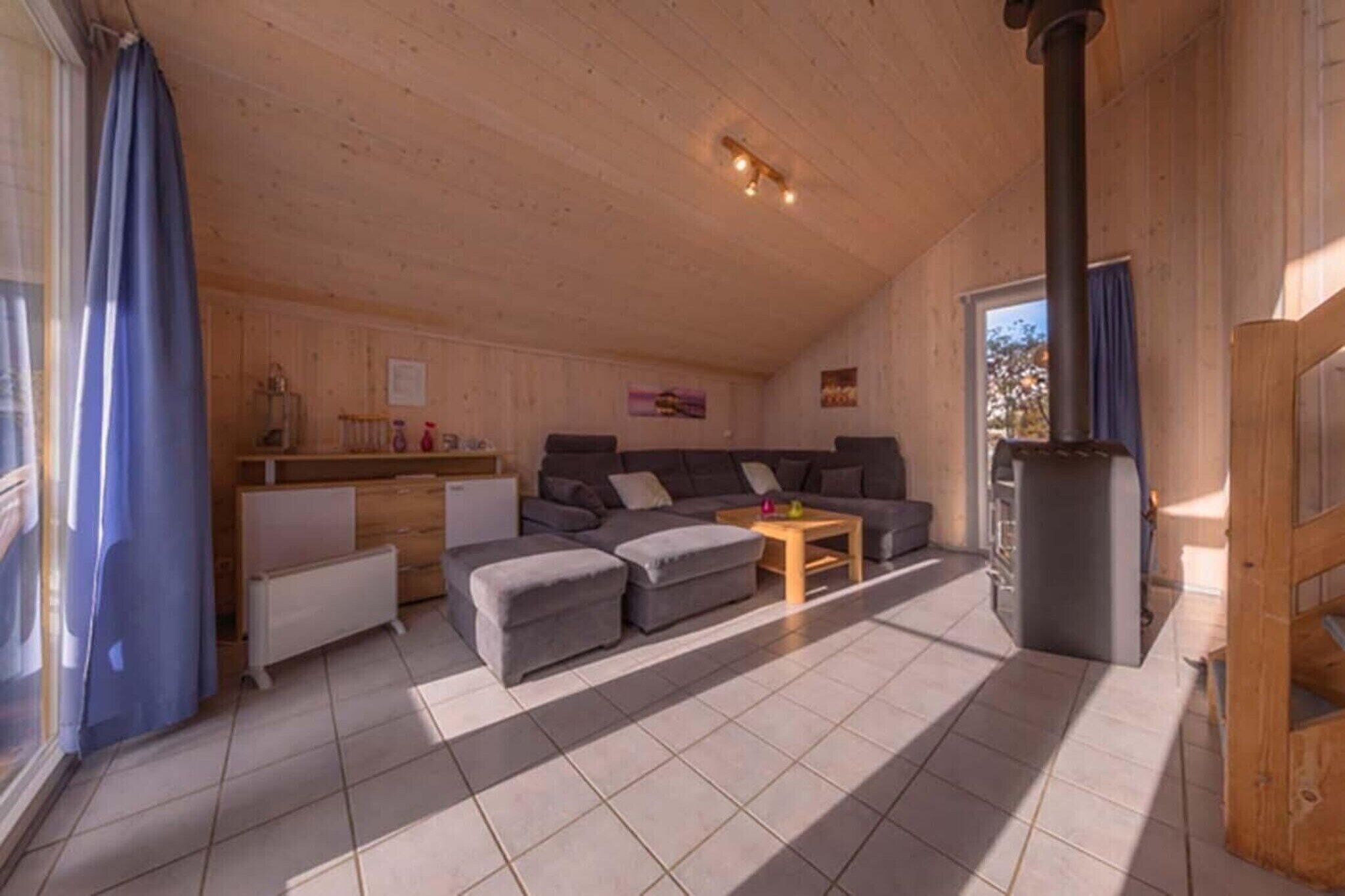 L’intérieur d’un chalet accueillant, avec un plafond en bois, un ensemble de canapés, une petite table et une cheminée.