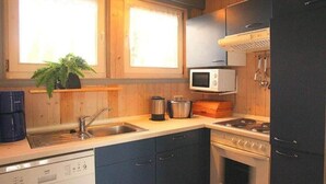 Una cocina con armarios de madera, microondas, estufa, lavaplatos y cafetera.