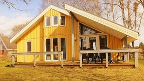 Una casa de madera amarilla con porche y un área de estar cubierta.