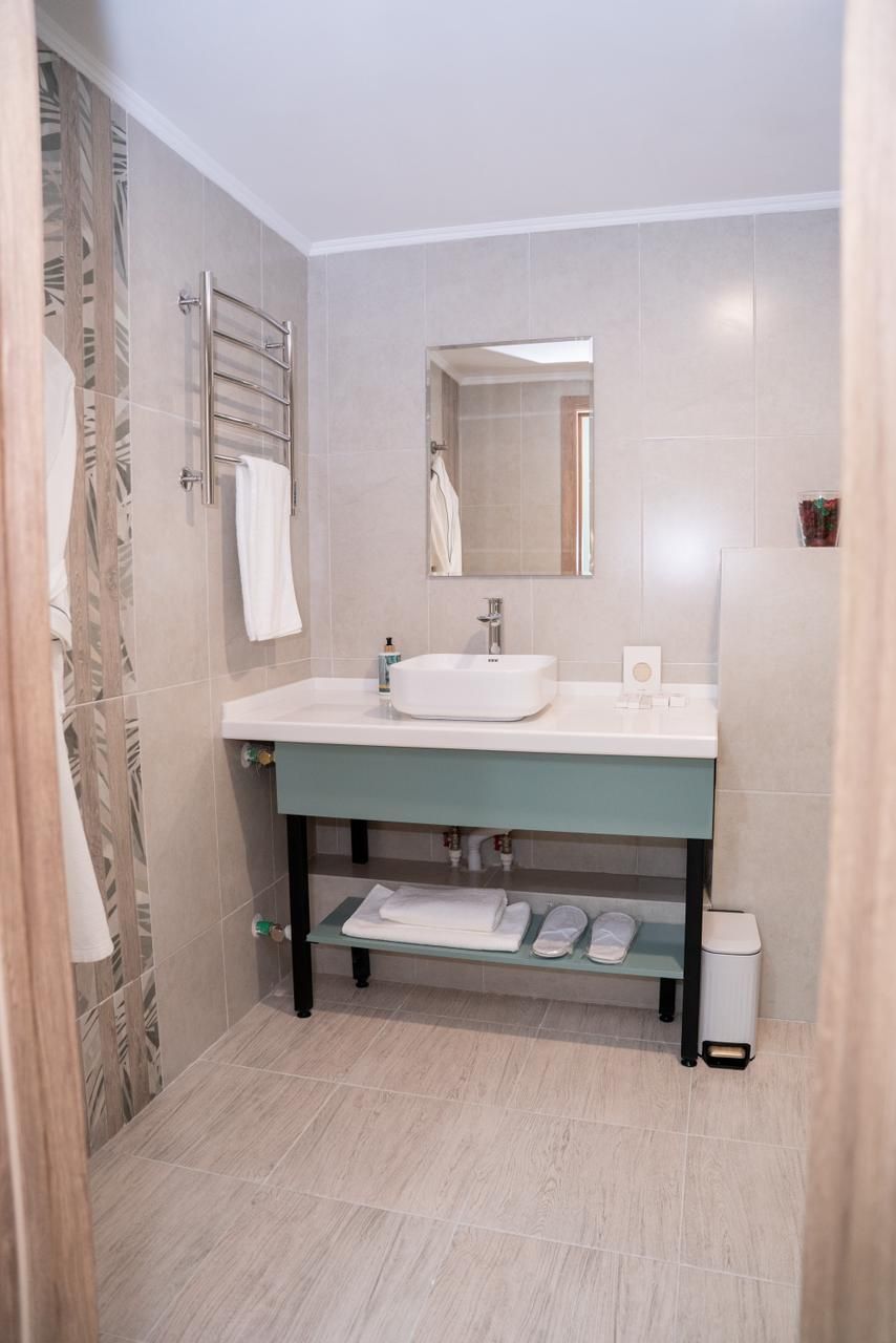 A bathroom with a white sink, a mirror, and a towel rack.