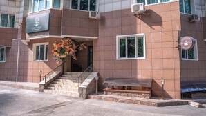 A hotel with a stone staircase leading to the entrance, a covered outdoor seating area, and a sign indicating the name of the hotel. - Terrenkur boutique-hotel (Almaty)