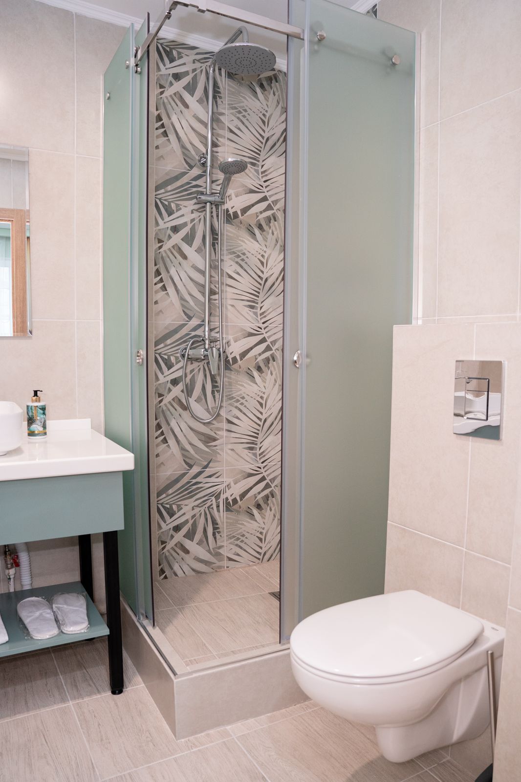Un baño con ducha envuelta en vidrio, un lavamanos blanco y un inodoro.