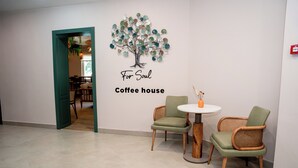 A coffee house with a wall art of a tree and the words "For Soul Coffee house". There are two wicker chairs and a small round table. - Terrenkur boutique-hotel (Almaty)
