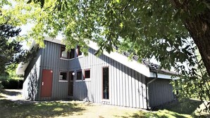Un bâtiment à deux étages, doté d’un toit en pente, d’une porte rouge et de nombreuses fenêtres.