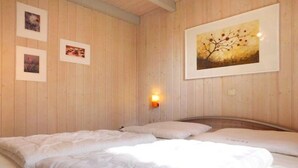 A room with a wooden paneled wall, a bed with white bedding, and three framed pictures. - skandinavisches Ferienhaus in Mirow (Granzow)