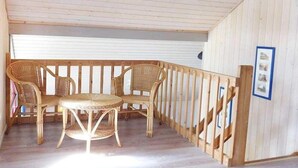 A covered outdoor seating area with wicker furniture and a wooden railing. - skandinavisches Ferienhaus in Mirow (Granzow)